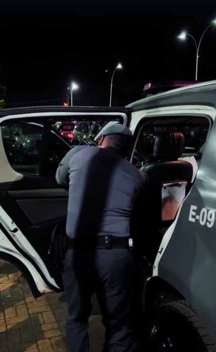 Policial junto à viatura durante diligência noturna
